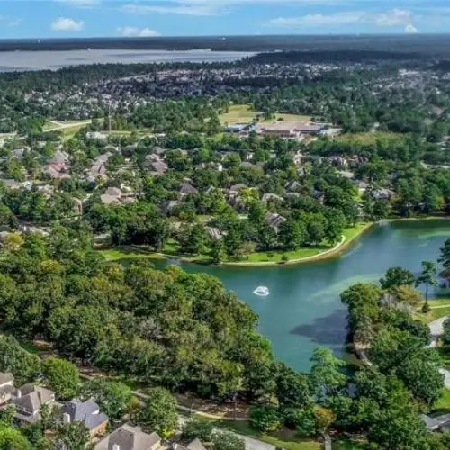 Aerial view of homes and trees beside a pond.